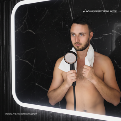 Man with towel using handheld shower in high-end black marble bathroom, highlighting skincare benefits