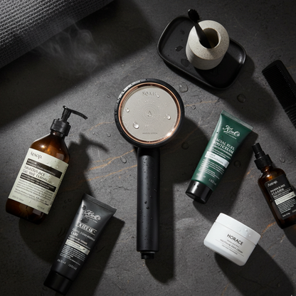 Luxury vitamin C shower head surrounded by high-end skincare brands on wet stone surface, flatlay composition