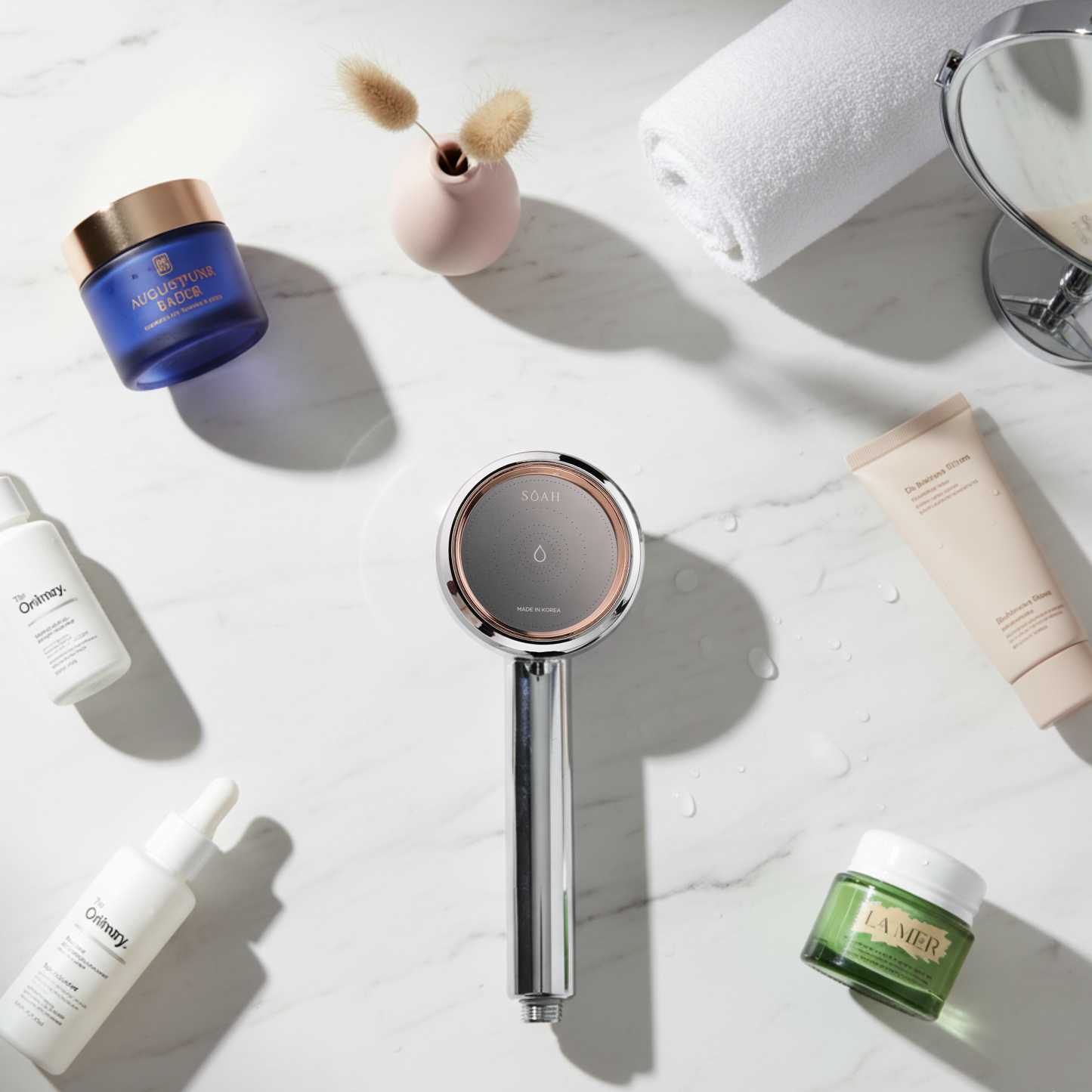 SOAH Vitamin C shower head displayed on marble next to high-end skincare brands like La Mer, The Ordinary and Augustinus Bader – highlighting water as the foundation of skincare.