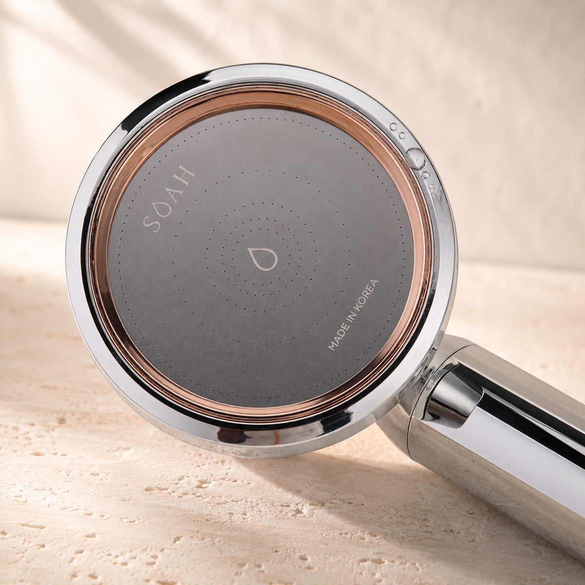 Close-up of the SOAH Chrome Edition spray face showing the micro-perforations, rose gold ring and Made in Korea engraving.