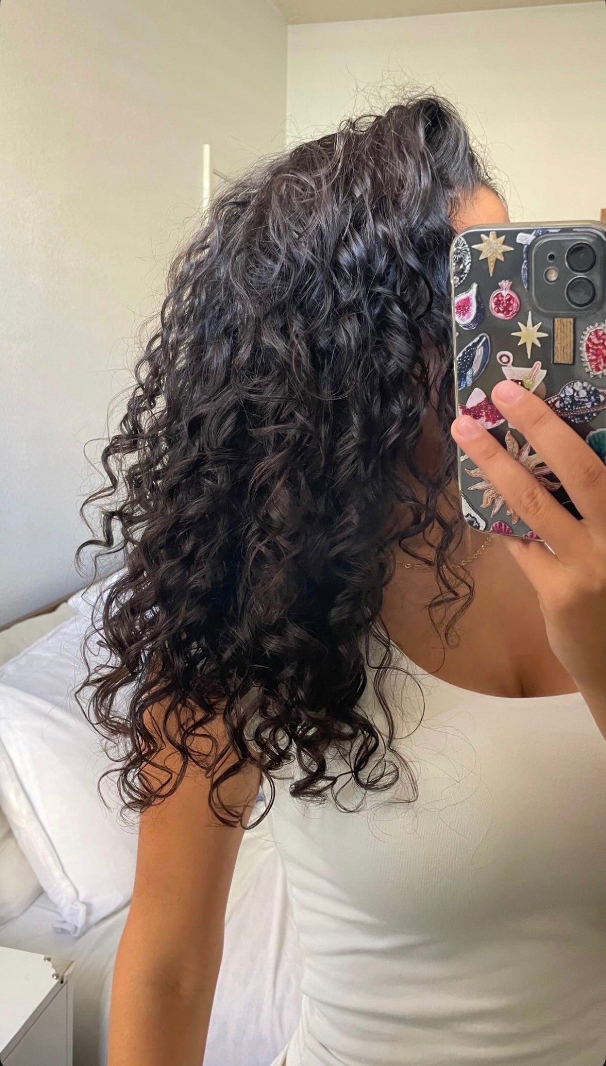 Woman with dark, defined curls taking a mirror selfie after using the SOAH vitamin C shower head, Maria from Al Barsha sharing how hard water damage to her curly hair improved